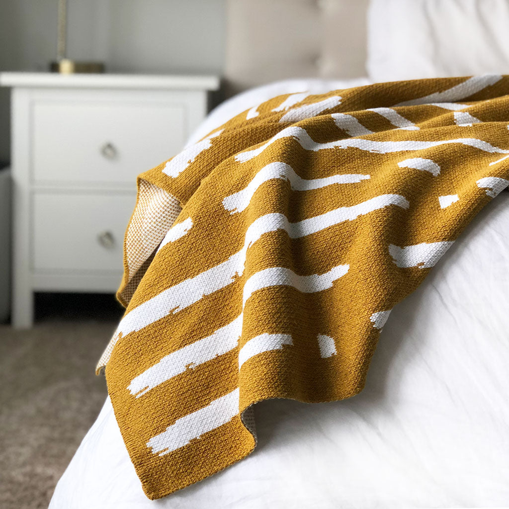 Seek & Swoon Diana Throw. Golden yellow and white in a bold, irregular graphic pattern.