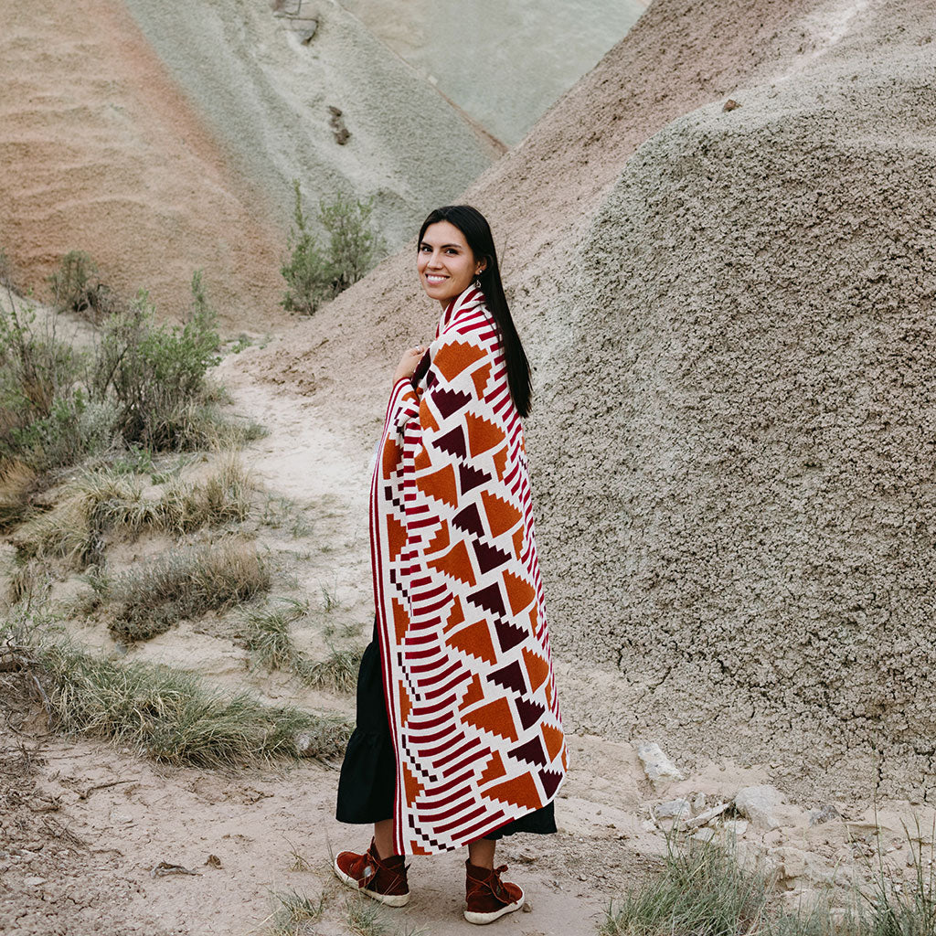 Seek & Swoon Sunset Mesa Throw in ivory, orange, and burgundy, with a geometric pattern.